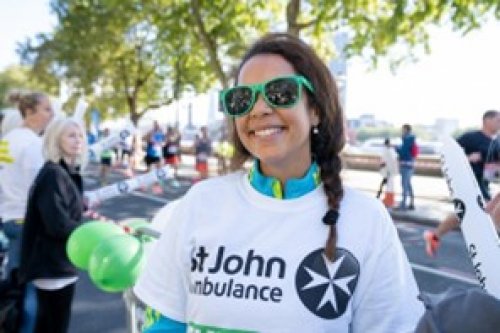 St John Volunteer at a running event, outside and smiling in branded t-shirt.
