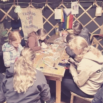 a group of young people sitting around a table working on art projects.