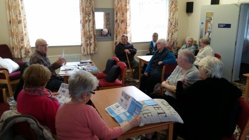 group of people sitting at tables talking and looking at leaflets