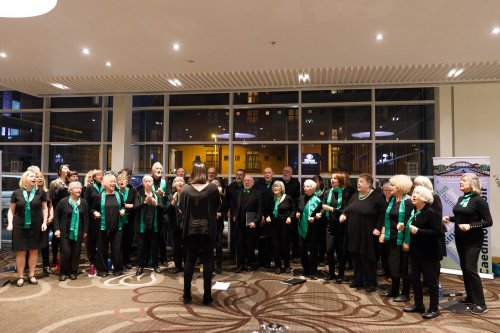 Picture of the choir rehearsing in a large modern hall