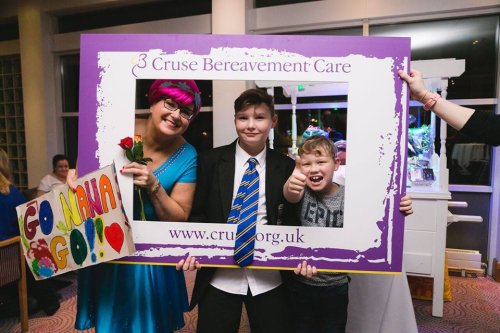 Two people fundraising for Cruse Bereavement Care, peeping through a large picture frame.
