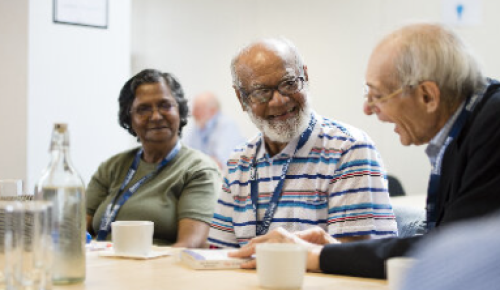 Three diverse committee volunteers sitting at a table having a friendly discussion