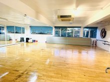 a large room with wooden flooring and one long mirrored wall.