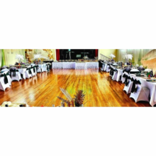 a large room with wooden flooring set out with decorated tables