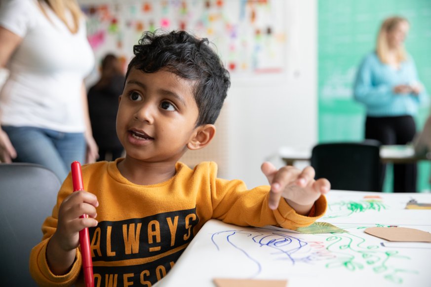 A child smiling whilst drawing 