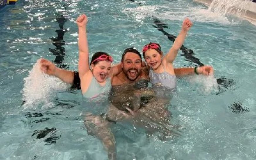 a father and 2 children having fun in the swimming pool