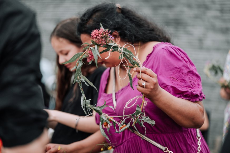 A person wearing pink holds a flower crown 