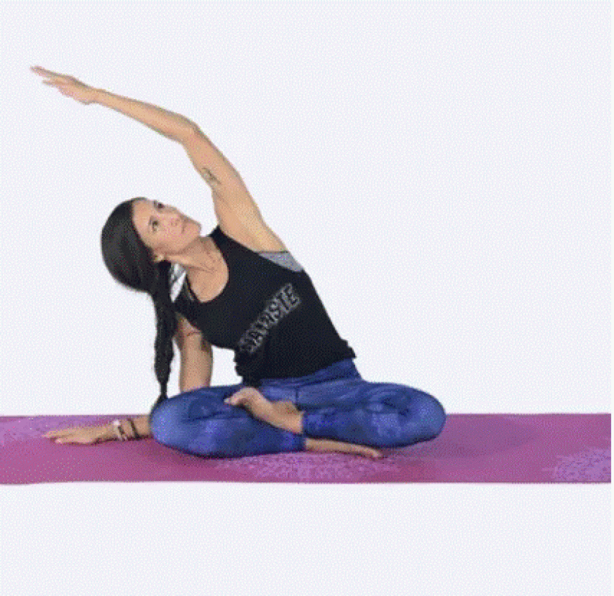 a women sitting on the floor in a yoga position leaning to one side with her arm stretching up over her head 