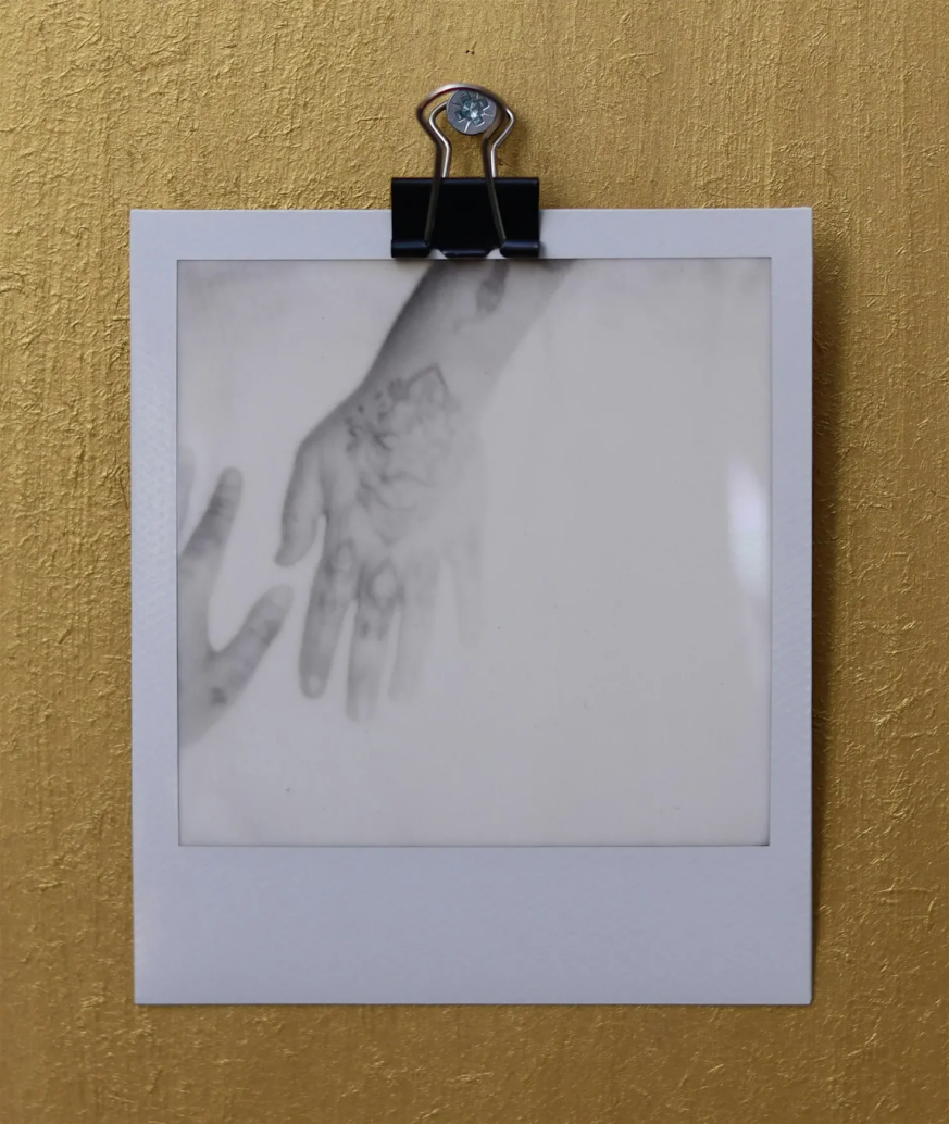 A black and white polaroid photo of a hand