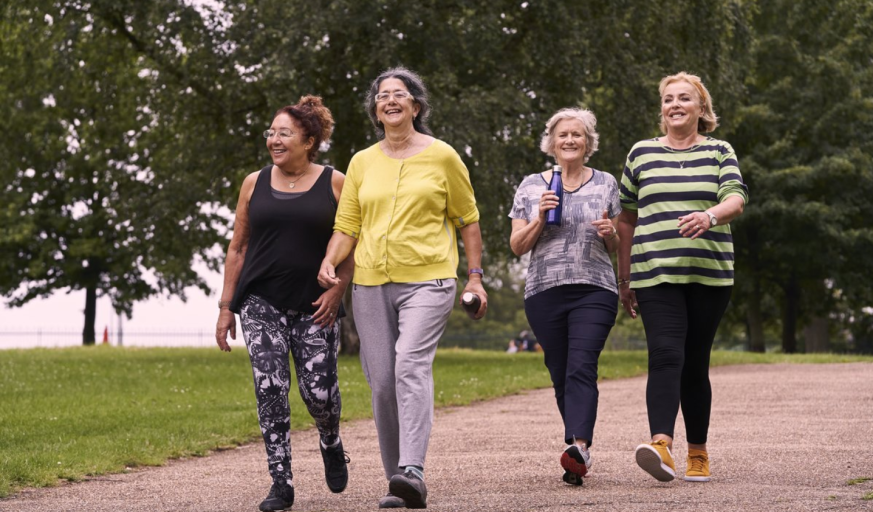 Four women walking over a path, smiling.