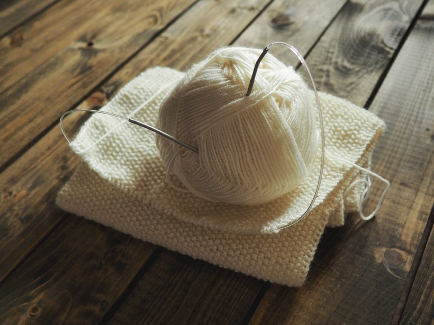 Ball of White Yarn with needle sticking inside from the top 
