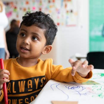 A child smiling whilst drawing 