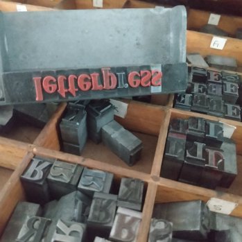 A box filled with an assortment of letter pressed metal stamps.