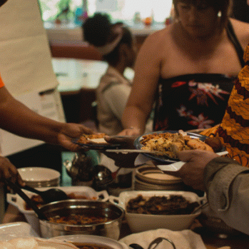a group of people surrounding a table, serving themselves with some delicious food 