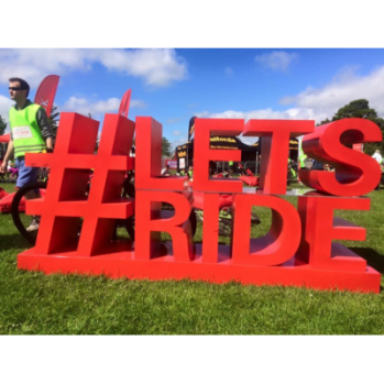 Huge sign outdoors spelling #Lets Ride in bold red letters