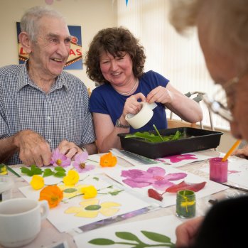 Picture of elderly man and woman smiling while doing a craft activity.