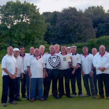 A group of the bowlers holding a shield trophy on the green