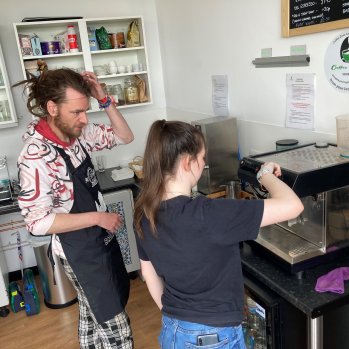 Two people in the kitchen using a barista coffee machine