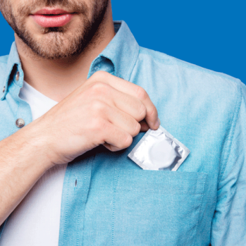 A close up of a man taking a condom out of his shirt pocket